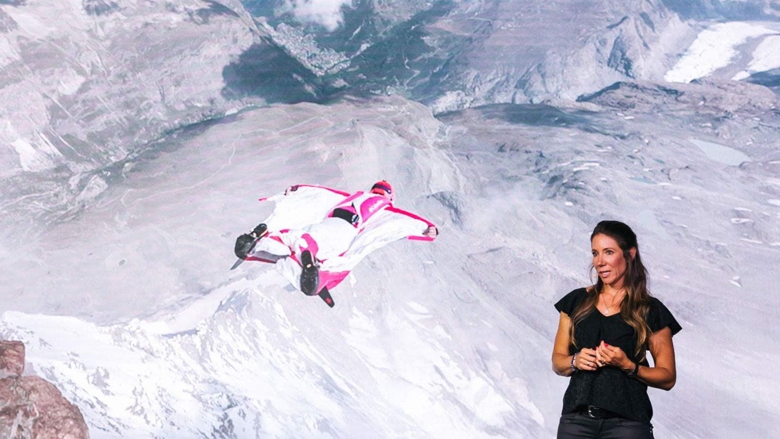 Géraldine Fasnacht sur scène, devant la projection d’un vol en wingsuit.