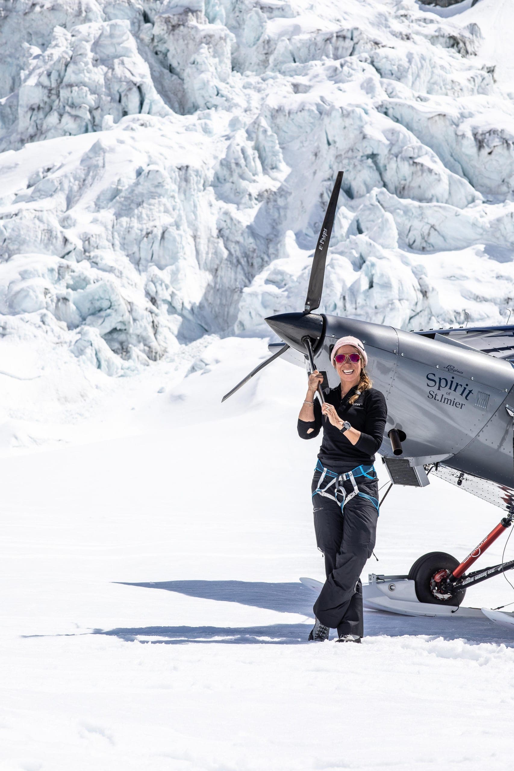 Géraldine Fasnacht devant l’hélice de son avion ultraléger posé sur un glacier, séracs en arrière-plan.